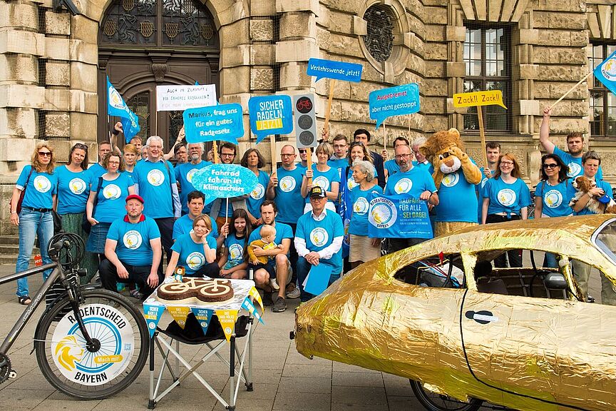Radentscheid Bayern unzulässig Eine Gruppe Radentscheid-Aktivist:innen vor dem Bayerischen Verfassungsgerichts-Gebäude in blauen T-Shirts.