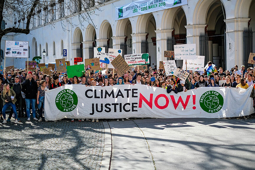 FFF Klimaschutz-Sofortprogramm Viele Menschen bei einer großen Demonstration von Fridays for Future. Sie halten ein großes Banner mit "Climate Justice now!".